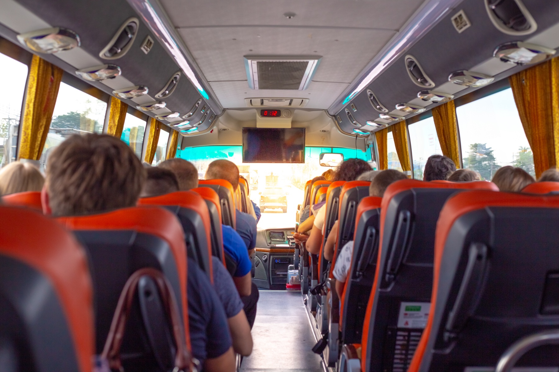 The back of heads and seats as you look forward on a tour bus