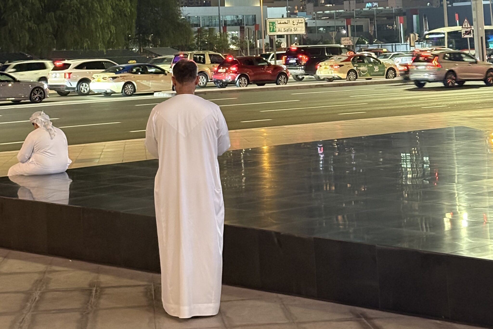 Two people look at a vibrant street in Dubai.