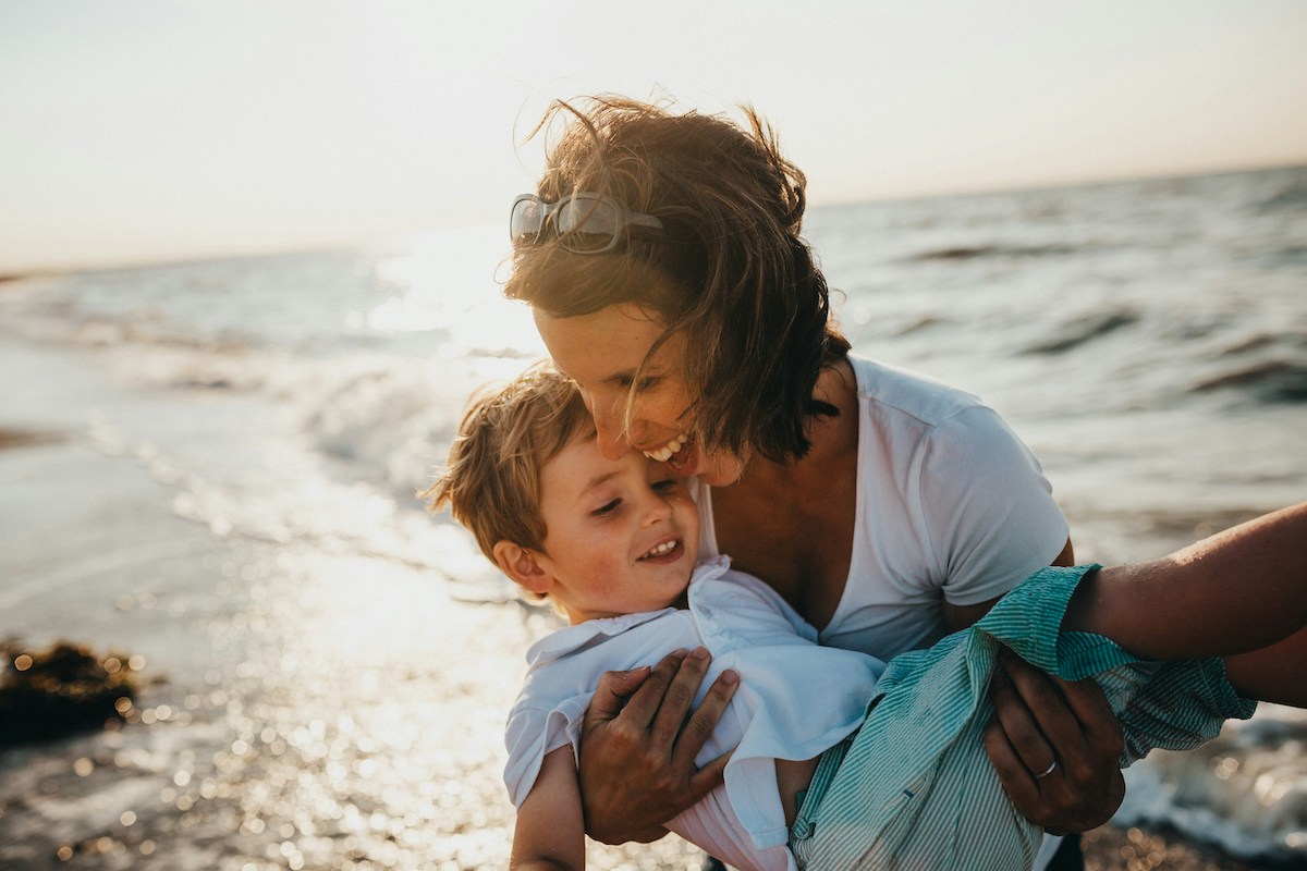 Woman holding toddler by shore