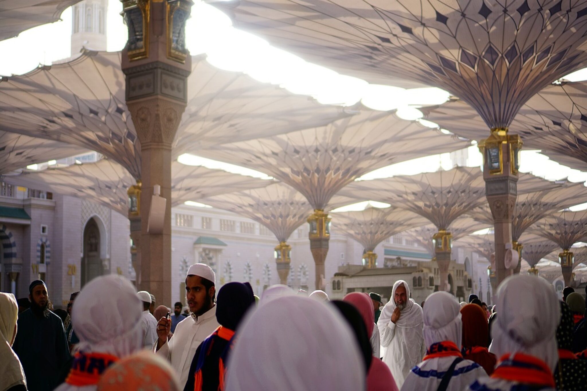 People walking under shading umbrella structures in Medina, Saudi Arabia