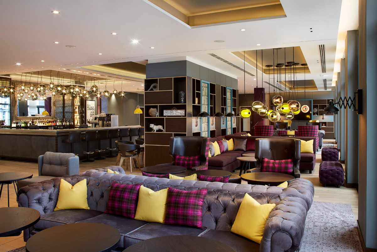 lobby of premier inn frankfurt messe hotel showing lots of couches with purple pillows