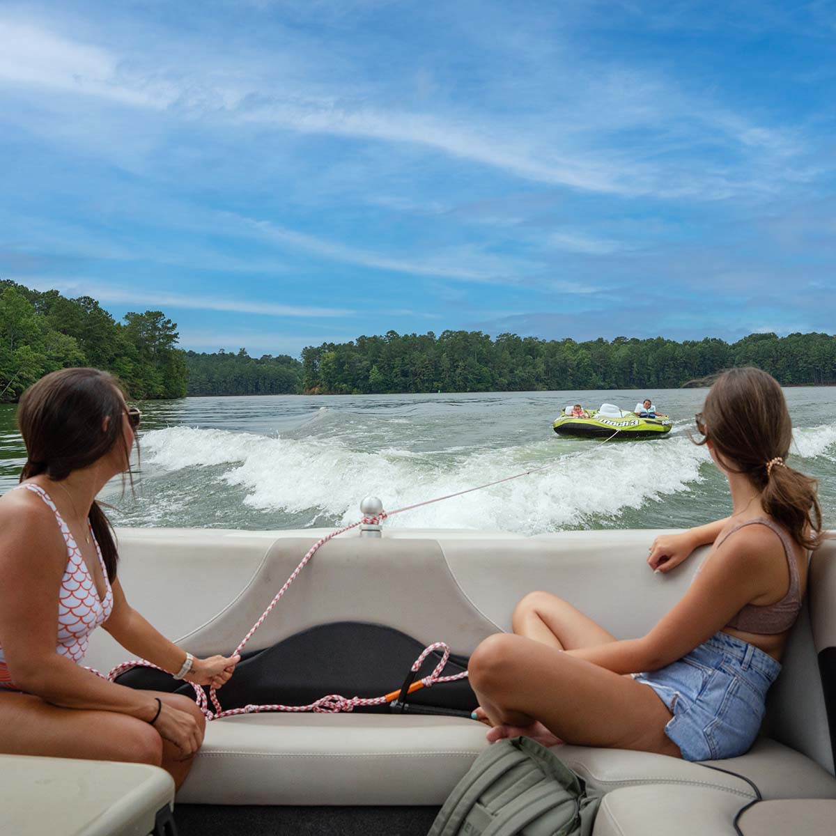 Women watching people ride on an inflatable tube, on West Point Lake.